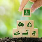 A hand stacks a pyramid of wooden blocks on which sustainability symbols and the DEKRA logo are depicted.