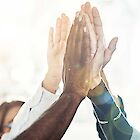 The arms of four people meet in the air for a high-five.