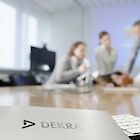 A document with the DEKRA logo on it. In the background you can see four people at a meeting.